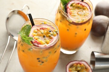 Tasty passion fruit drink with mint in glasses and fresh fruits on gray table, closeup