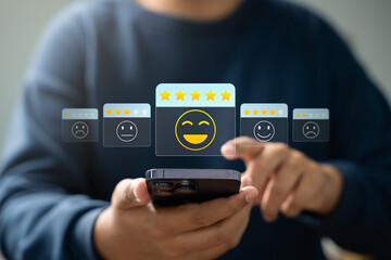 Satisfaction review, User giving five-star rating with happy emoji icon on smartphone screen, representing excellent customer feedback, digital reputation, and mobile user experience concept.