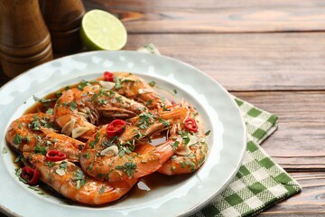 Tasty grilled shrimps with spices and sauce on wooden table, closeup. Delicious seafood dish