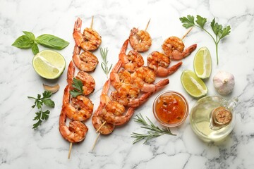 Skewers with tasty grilled shrimps, lime slices, herbs, oil and sauce on white marble table, flat lay. Delicious seafood dish