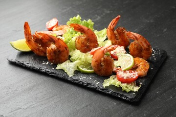 Tasty grilled shrimps with salad on black table, closeup. Delicious seafood dish