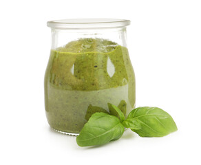 Pesto sauce in jar and fresh basil leaves isolated on white