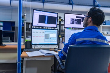 Inside the large Industry Factory male Computer Engineer Works on Personal Computer She coding program for control machine,Thailand people work on fours monitors,Programmer working with serious