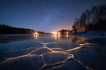 rozen lake glowing with butter yellow cracks of light beneath ice snow falling under starry sky concept of fantasy photography winter holiday scene and magical seasonal 