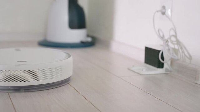 Robot vacuum cleaner glides smoothly across wooden floor during cleaning cycle, showcasing modern smart appliance efficiency and automated home technology for household maintenance