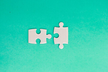 Two puzzle pieces on a teal background symbolizing connection and solutions in business and teamwork