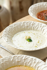 Variety of gourmet soups in textured ceramic bowls on a wooden table in a cozy cafe interior