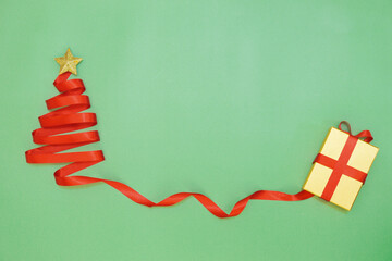 Red ribbon Christmas tree and gift box on green background. Christmas background.