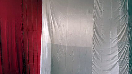 Draped fabric resembling an Italian or Indonesian flag, partially concealed, showing red, white, and green sections.