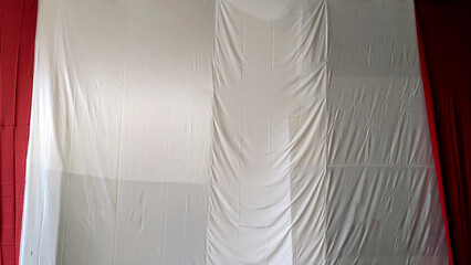 Draped fabric resembling an Italian or Indonesian flag, partially concealed, showing red, white, and green sections.