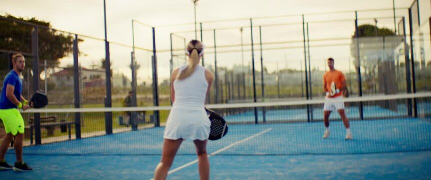 Young people enjoying an active game of padel on a sunny outdoor court