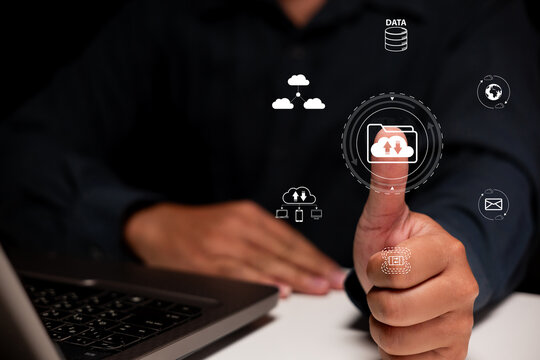 A person is giving a thumbs-up while interacting with digital cloud data icons on a laptop, symbolizing successful data management and technology use.