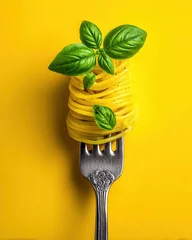 Sierkussen Restaurant Fork with twirled spaghetti and fresh basil leaves against vibrant yellow background  © saichon