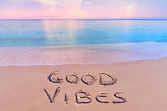 handwritten good vibes on sandy beach at sunset - Powered by Adobe