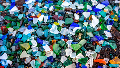 Colorful shards of broken glass, scattered across a surface, creating a vibrant mosaic pattern.