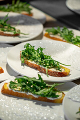 Fresh bruschettas being prepared with cream cheese and arugula