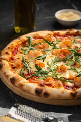 Shrimp and arugula pizza with cheese and tomato sauce on dark stone background