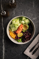 Healthy poke bowl with salmon, avocado, cucumber and vegetables