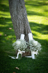 Bridal bouquet made of small white flowers placed on green grass near a tree, symbolising purity, romance and natural elegance