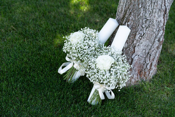 Bridal bouquet made of small white flowers placed on green grass near a tree, symbolising purity, romance and natural elegance