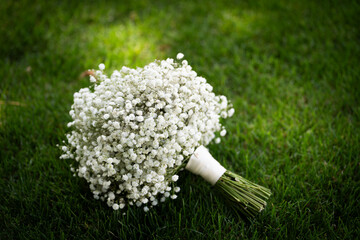 A beautiful bridal bouquet resting on green grass, featuring delicate flowers in soft, romantic colors. Perfect for wedding, romance, or outdoor celebration themes