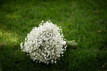 A beautiful bridal bouquet resting on green grass, featuring delicate flowers in soft, romantic colors. Perfect for wedding, romance, or outdoor celebration themes