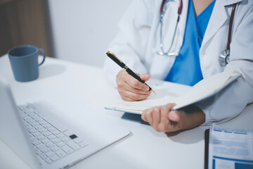 Middle aged female doctor working on laptop in doctor's room