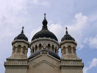 Fototapeta premium Dormition of the Theotokos Cathedral in Cluj-Napoca, Romania, features a Neo-Byzantine architectural style. The facade showcases three ornate domes, with the central one being larger 