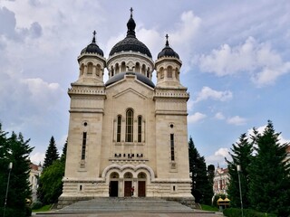 Fototapeta premium Dormition of the Theotokos Cathedral in Cluj-Napoca, Romania, features a Neo-Byzantine architectural style. The facade showcases three ornate domes, with the central one being larger 