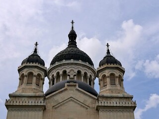 Fototapeta premium Dormition of the Theotokos Cathedral in Cluj-Napoca, Romania, features a Neo-Byzantine architectural style. The facade showcases three ornate domes, with the central one being larger 