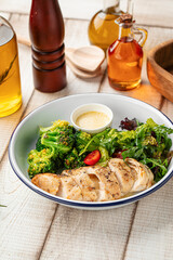 Healthy lunch bowl with grilled chicken, fresh salad and broccoli on rustic wooden table