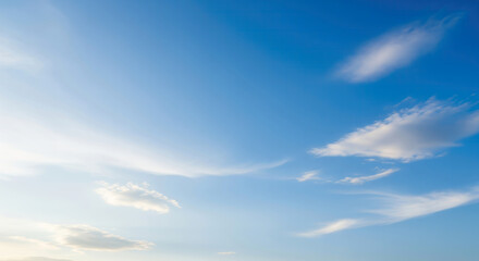 Obraz premium A serene blue sky featuring soft, wispy white clouds scattered across a beautiful natural gradient, creating a calming and peaceful atmosphere.