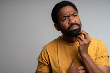 Thinking black man close up holding chin isolated on background