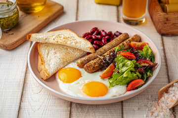 Portion of classic english breakfast with fried eggs, sausages and beans