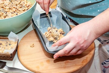 A woman carefully places the batter into a loaf pan, preparing for baking in a cozy kitchen.