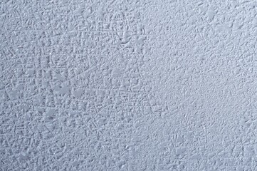 Close-up of delicate ice crystals forming intricate patterns on a window during a cold winter day.