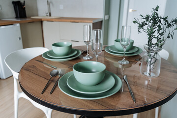 An Elegant Dining Setup Featuring Chic Green Tableware and a Minimalist Decor Aesthetic in a Modern Kitchen Setting, Perfect for Entertaining Guests at Fine Dinner Parties