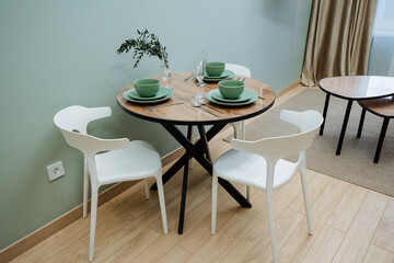 This modern dining table features vibrant green dishes and elegant decor, creating an inviting atmosphere for contemporary cooking and enjoyable dining, embodying a minimalist aesthetic