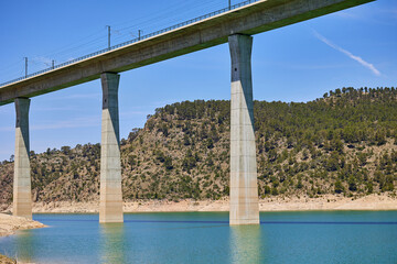 Tranquil scenery under a bridge over a reservoir with crystal clear turquoise water