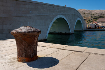 Naklejka premium Rusty Mooring Bollard and Stone Arch Bridge in Pag Croatia