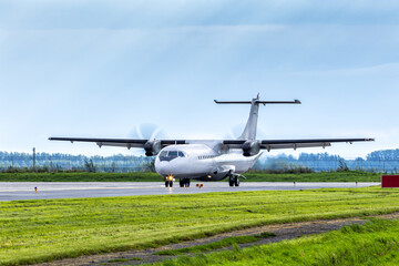 White passenger turboprop aircraft taxis along the main taxiway at airport