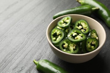 Whole and cut green jalapeno peppers on grey table, closeup. Space for text