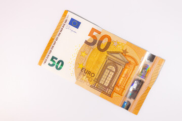 Close-up of a 50 euro banknote on a white background, symbolizing finance, currency, savings, wealth, or economic value.