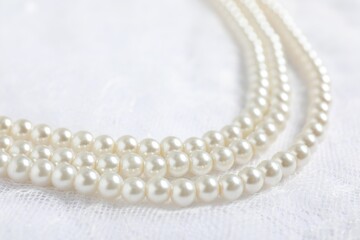 Beautiful pearl necklace on lace fabric, closeup
