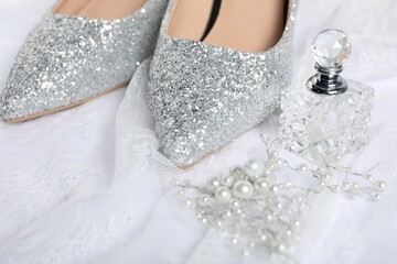 Beautiful shoes, perfume, pearl accessory and lace fabric on white background, closeup