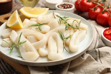 Uncooked squid rings, spices and tomatoes on table, closeup