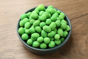 Delicious wasabi coated peanuts in bowl on wooden table, closeup