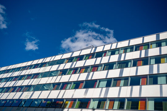 Colorful façade of Stockholm modern building with rectangular windows reflecting sky, Scandinavian architecture emphasizing geometry, transparency and innovative urban design detail clarity 