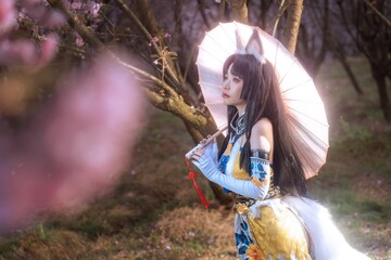 Stunning fox spirit cosplayer with umbrella amidst blooming cherry blossoms evokes fantasy and beauty, perfect for editorial, gaming, or creative projects