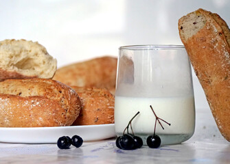 Freshly baked bread and milk - Fresh Bread Rolls, a Glass of Milk, and Berries on a Table